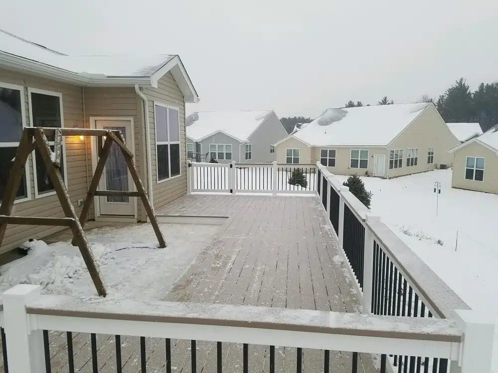 Deck with white railing covered in snow, attached to a house photo - Hen House Decks
