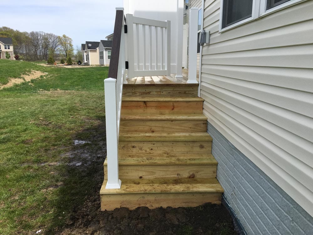 Wooden deck stairs without railings leading to a white-sided house photo - Hen House Decks