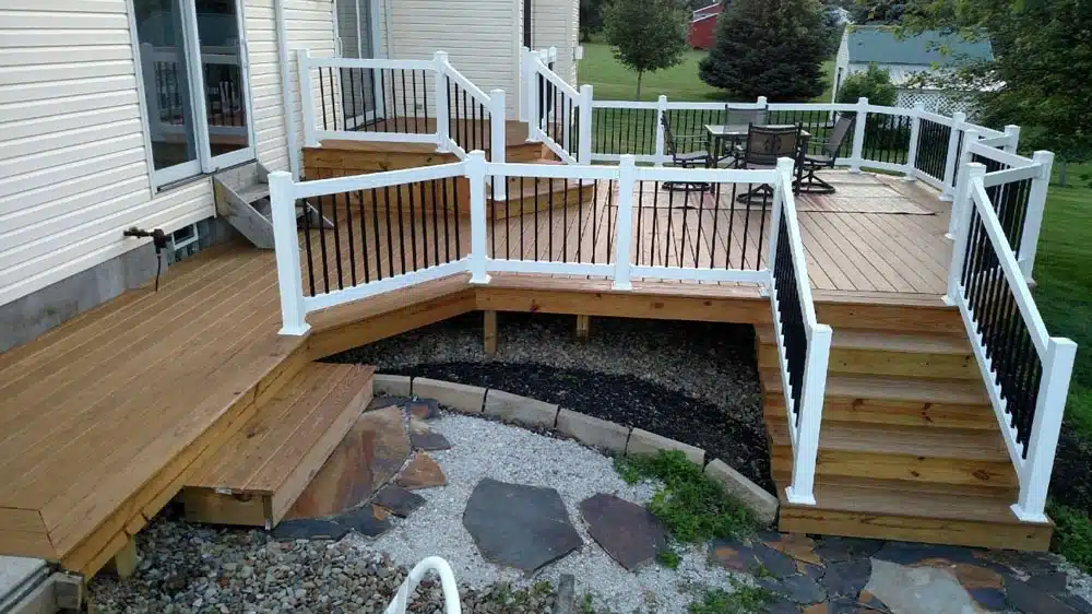 Corner view of a deck with white railings and black spindles, featuring a stone pathway leading to the garden in Summit County photo