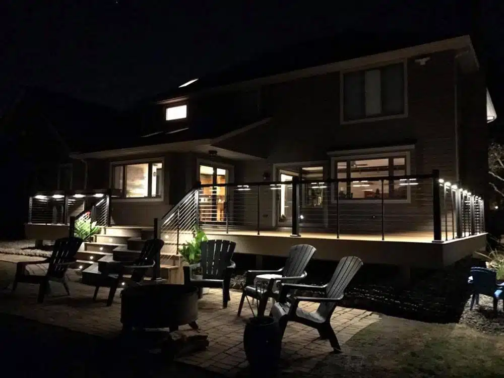 Deck at night with outdoor furniture and ambient lighting under a second-story deck
