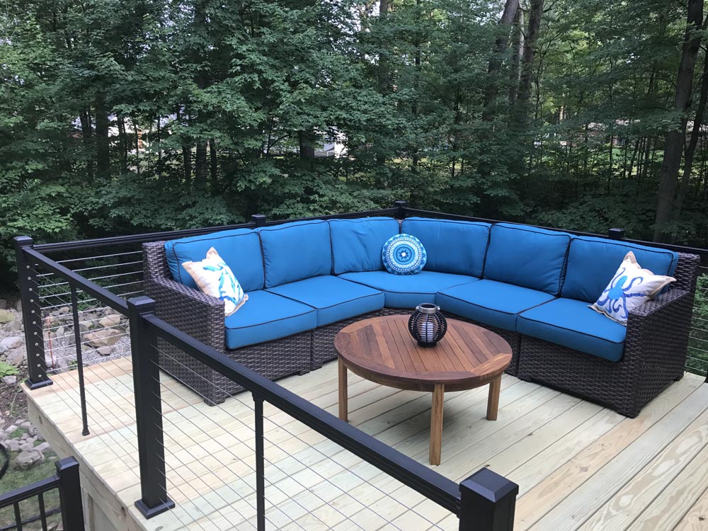 Backyard deck with blue pool loungers and a small table, bordered by a black railing
