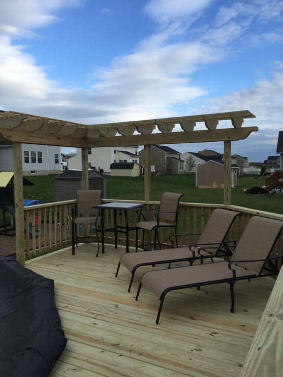 Backyard wooden deck with white railings and a pergola, complete with outdoor furniture