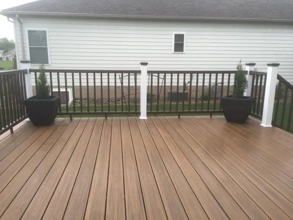 Wooden deck with white railings and stairs leading to a backyard with bare trees.