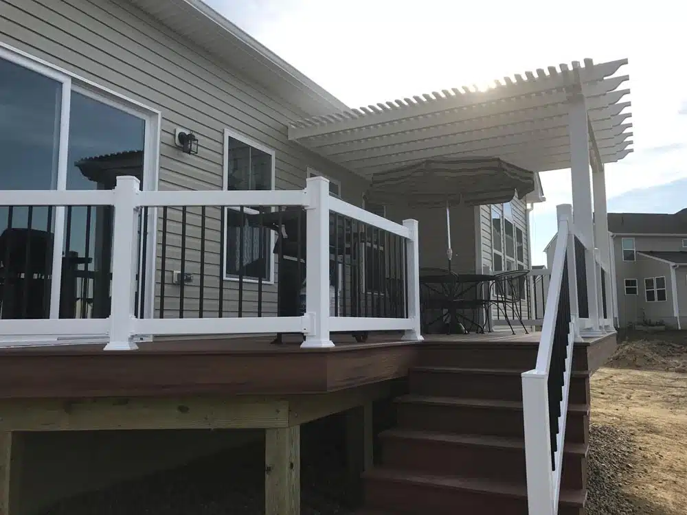 House with an elevated deck, featuring white railings and black balusters.