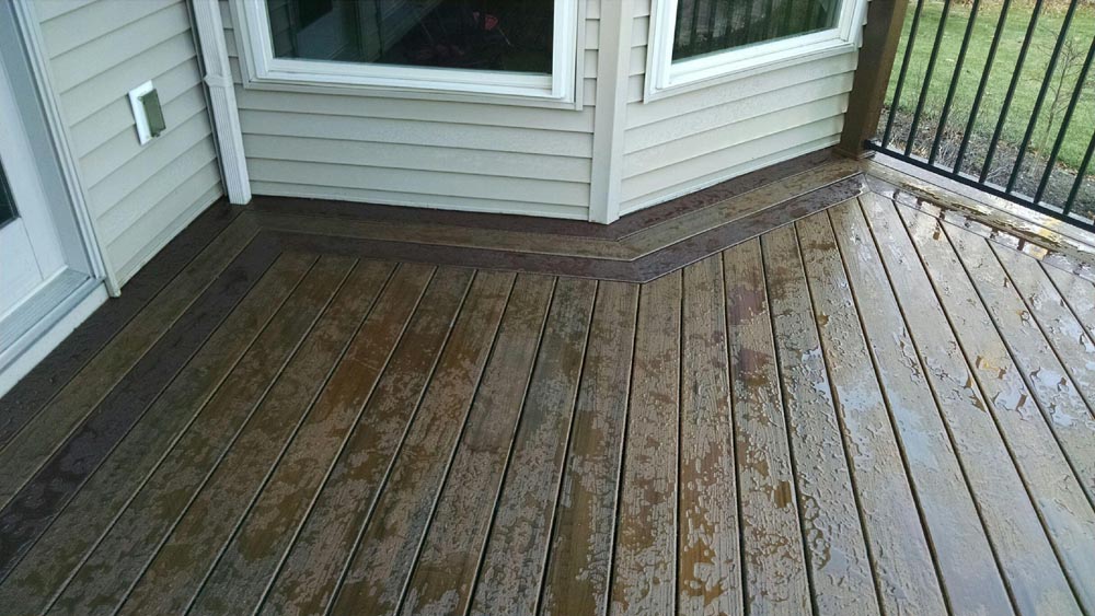 Close-up of a wet wooden deck with the house siding in view