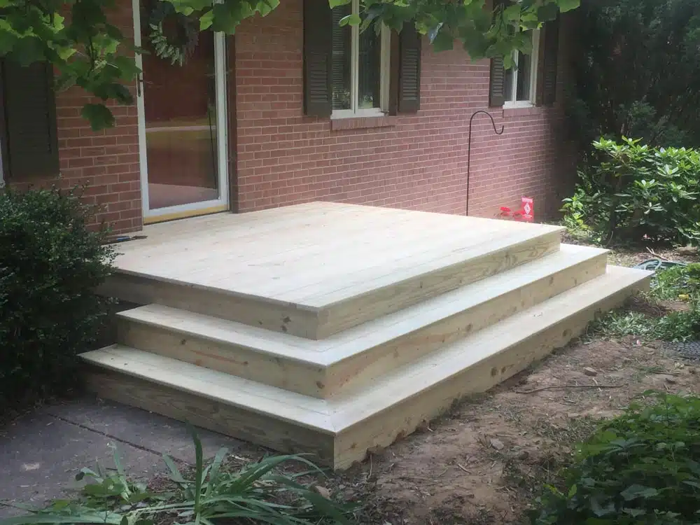 Concrete patio steps leading up to a pink brick house with white siding