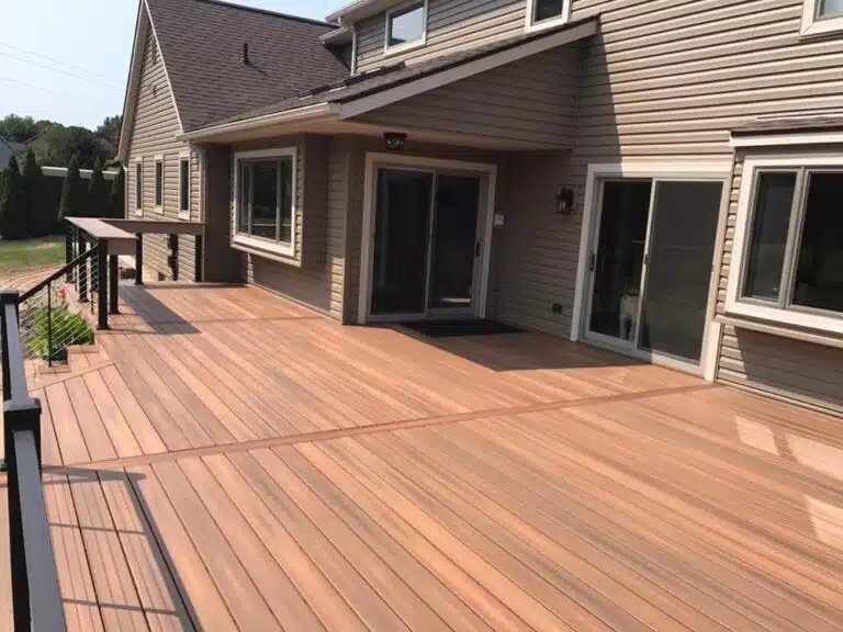 Wooden deck attached to a house, featuring a covered area with a slanted roof.