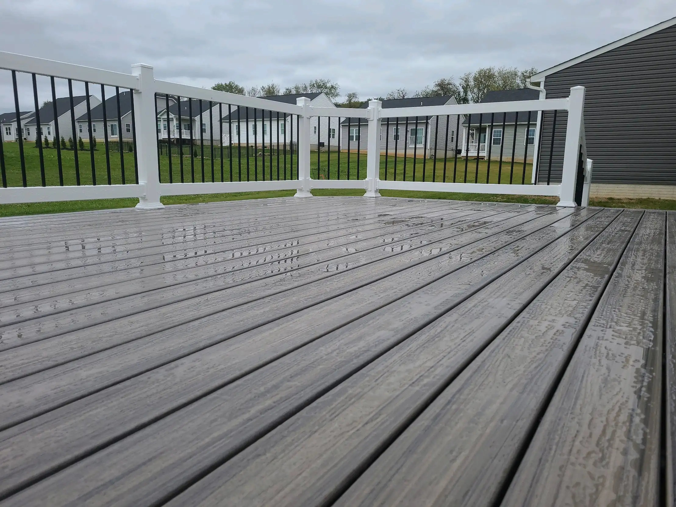 Deck Resurfacing Cost Gray Composite Deck with White Railings — Low‑maintenance deck example showing white railing and black balusters