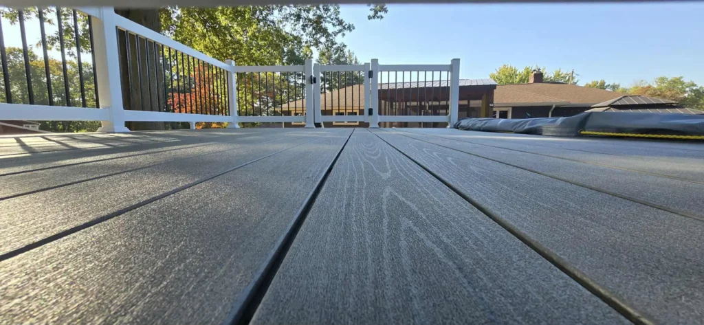 Home 7 Low-angle view of a gray composite deck with white vinyl railing, black metal balusters and a center safety gate — illustration for deck resurfacing cost in Ohio
